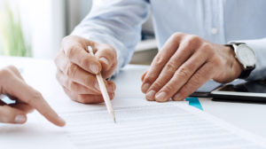 Two people having a discussion and pointing to a piece of paper related to their business.